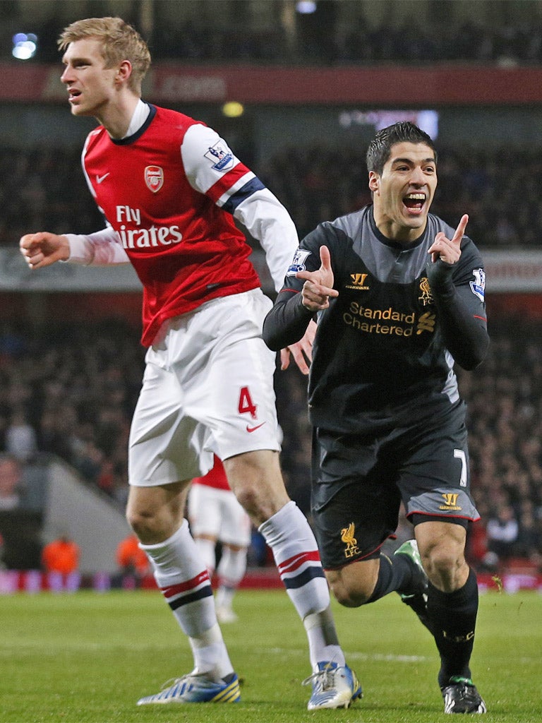 A stunned Per Mertesacker looks on as Suarez runs off celebrating giving Liverpool the lead