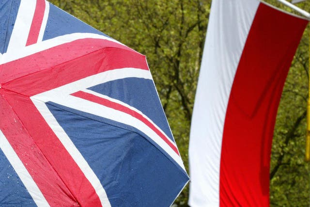 A pedestrain takes shelter under an umbrella with Union Jack on it as they walk past the Polish flag on the Mall in London 05 May, 2004. The British capital was dressed in red and white to welcome Polish President Aleksander Kwasniewski who was on a State Visit.
