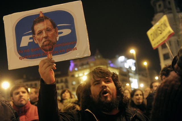 January 31, 2013: A  man holds a placard depicting Spanish Prime Minister Mariano Rajoy and reading "We don't even want resignations, we want heads on spike" as he takes part in a demonstration against corruption scandals implicating the PP (Popular Party