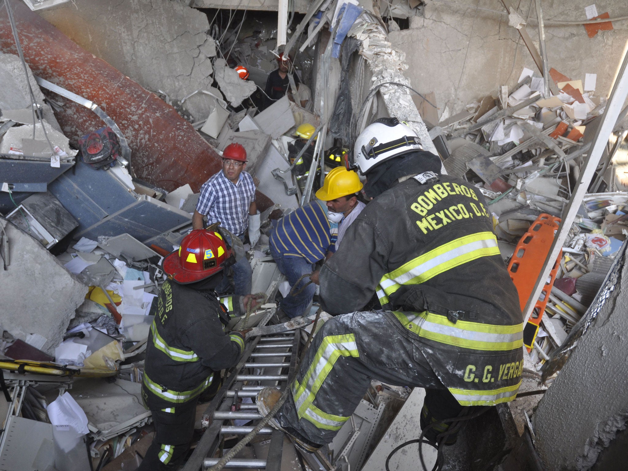 Firefighters dig for survivors after the explosion at an adjacent building to the executive tower of Mexico's state-owned oil company Pemex