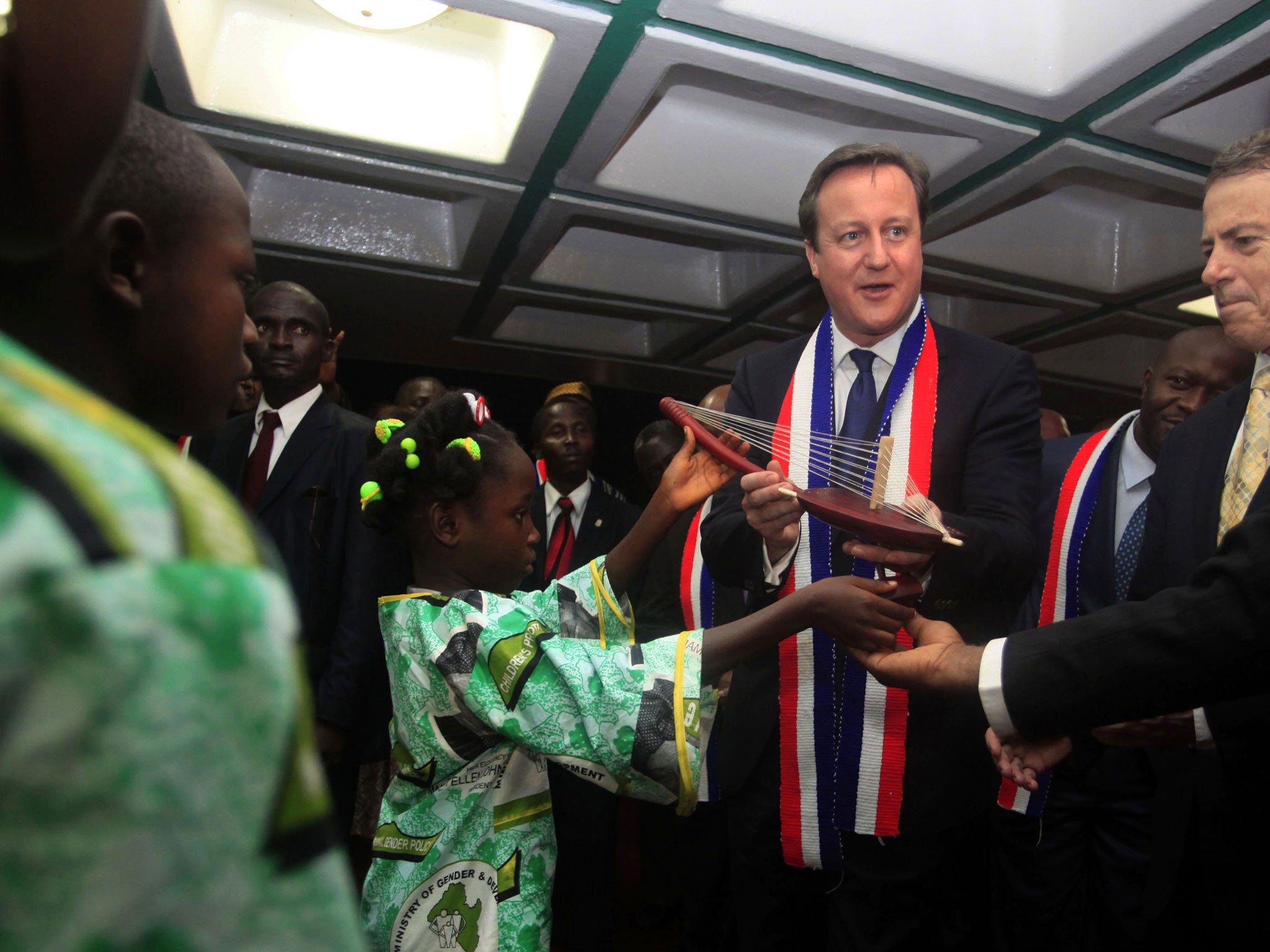 David Cameron receives a gift from a Liberian girl as he arrives at Roberts international airport in Monrovia