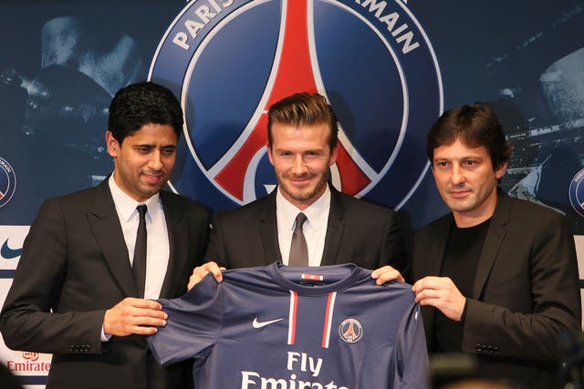 David Beckham (C) poses presenting his new shirt flanked by PSG Qatari president Nasser Al-Khelaifi (L) and PSG sports director Leonardo
