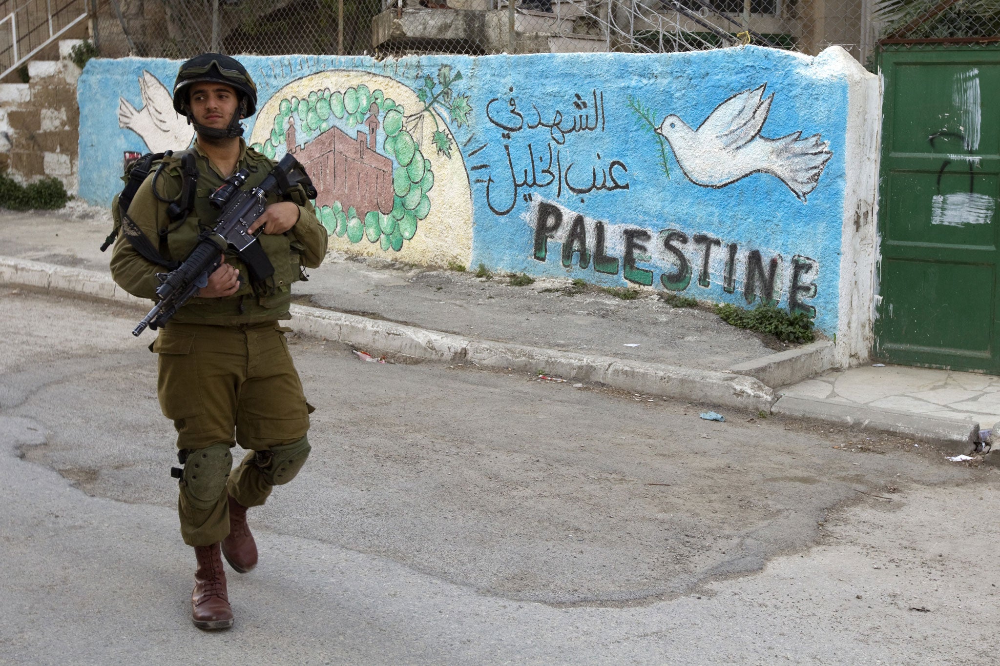 An Israeli soldier patrols near a Palestinian house in the centre of Hebron in the occupied West Bank on April 3, 2012