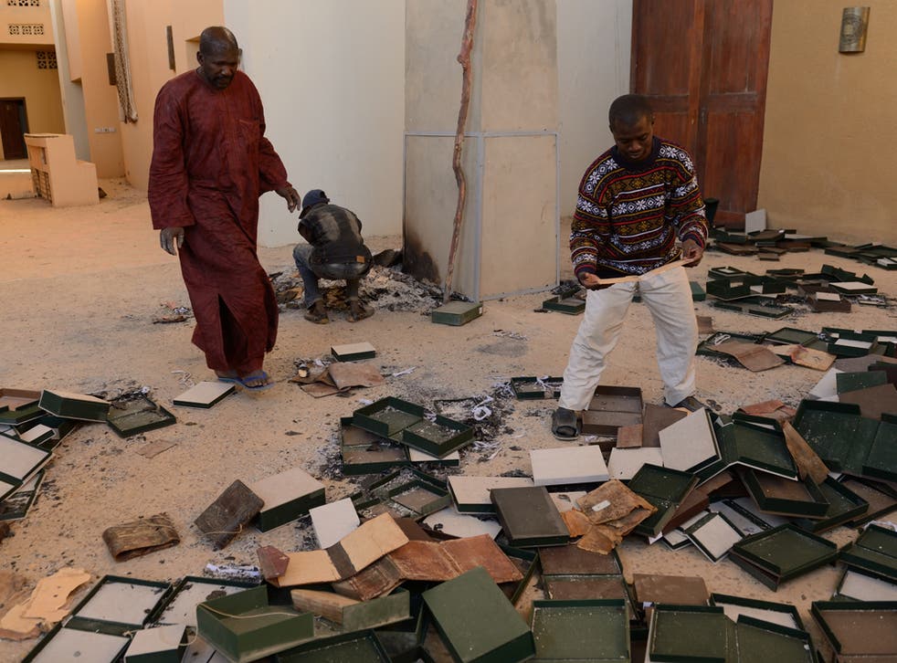 Men recover burnt ancient manuscripts at the Ahmed Baba Centre for Documentation and Research in Timbuktu