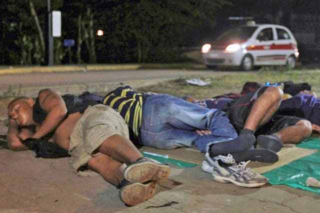 Central American immigrants waiting to board a train, sleep next to a road in Coatzacoalcos, Veracruz state. Thousands of immigrants seeking to reach the US border, are encamped in the village of Coatzacoalcos in hopes that the train called The Beast passes to continue their travel