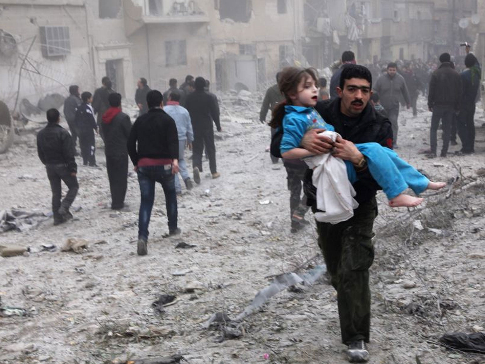A man holds a child in his arms in Aleppo, Syria after an airstrike