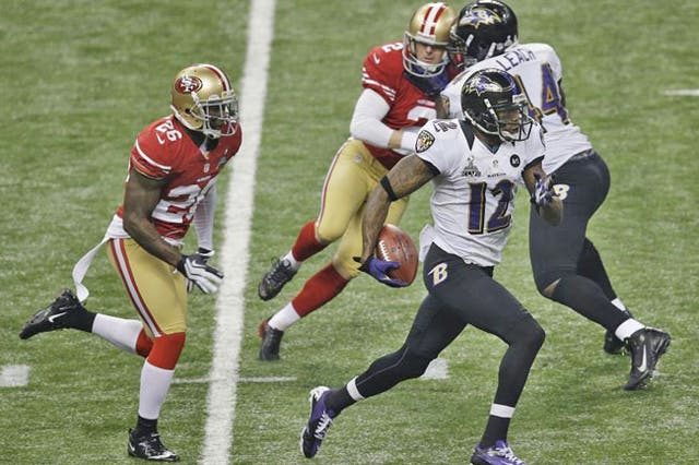 Baltimore Ravens wide receiver Jacoby Jones (12) runs past San Francisco kicker David Akers (2) and Tramaine Brock (26) as he returns the kickoff for a touchdown during the second half of  the NFL Super Bowl XLVII football game