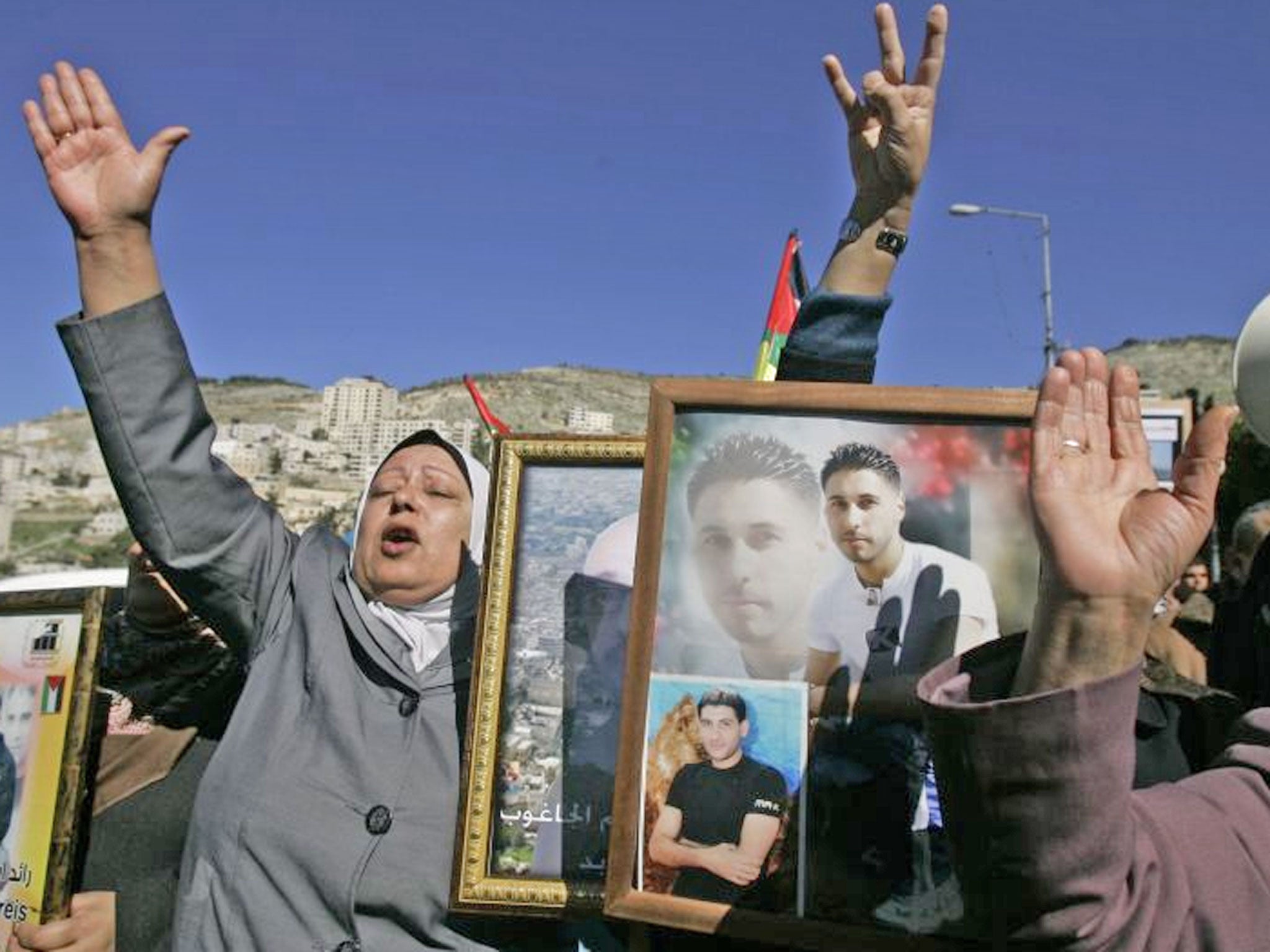 Palestinian women hold pictures of prisoners jailed in Israel during a rally calling for their release, in the West Bank city of Nablus. Israeli forces arrested over 20 members of the Palestinian militant group Hamas, including three lawmakers