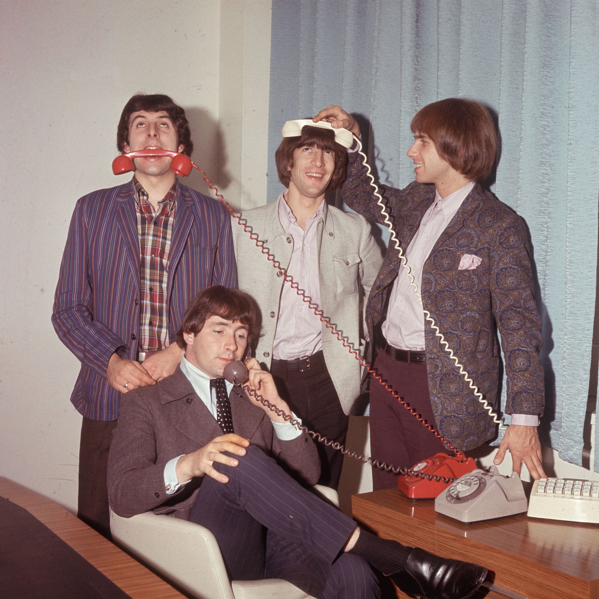 Circa 1966: The British pop band 'The Troggs', Reg Presley, (front) Chris Britton, Peter Staples and Ronnie Bond, posing with three telephones.
