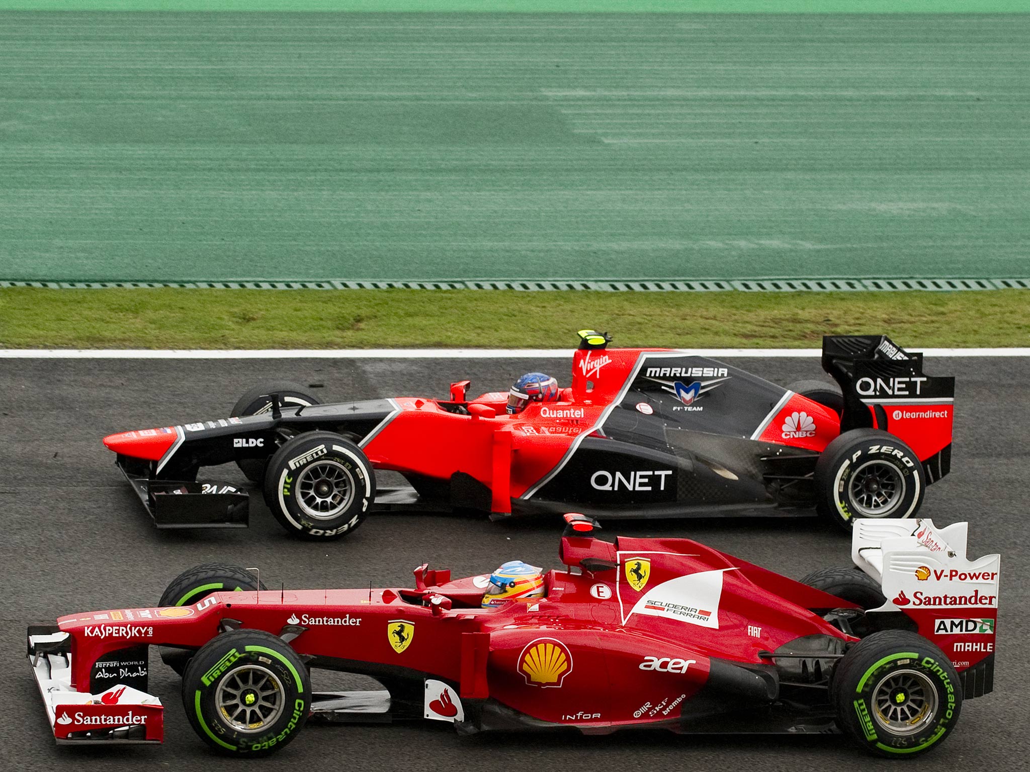 Spanish Formula One driver Fernando Alonso (front) powers his Ferrari to overtake Charles Pic of Marussia during testing