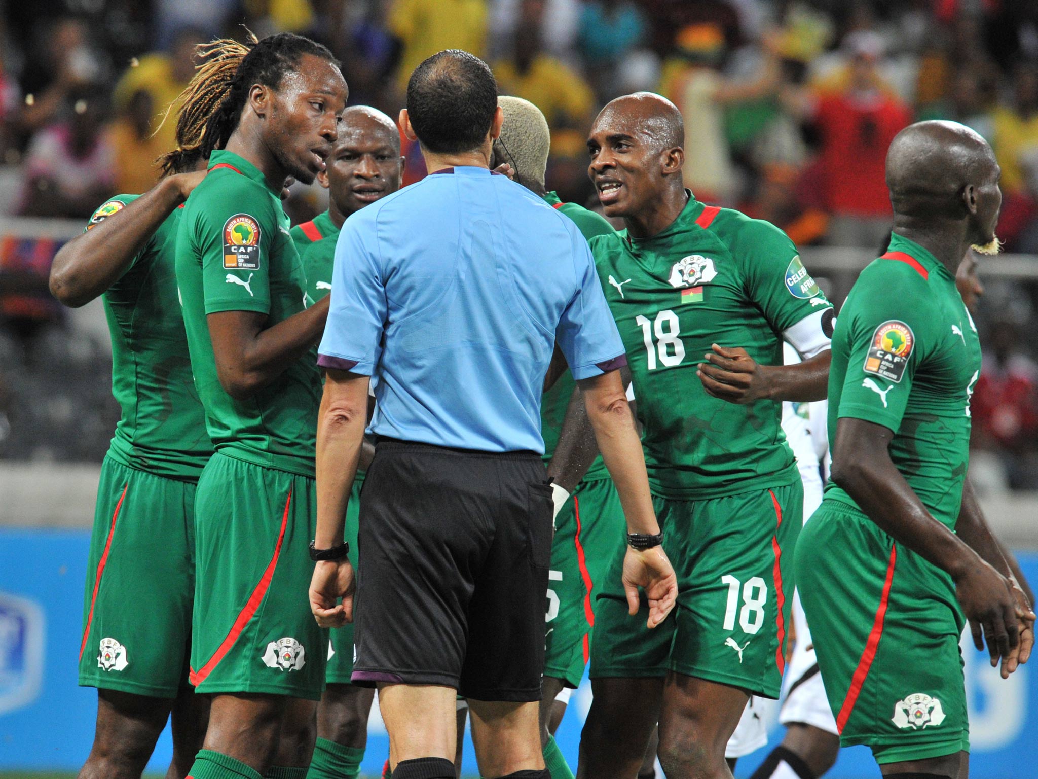 Burkina Faso's players argue with Tunisian referee Slim Jdidi