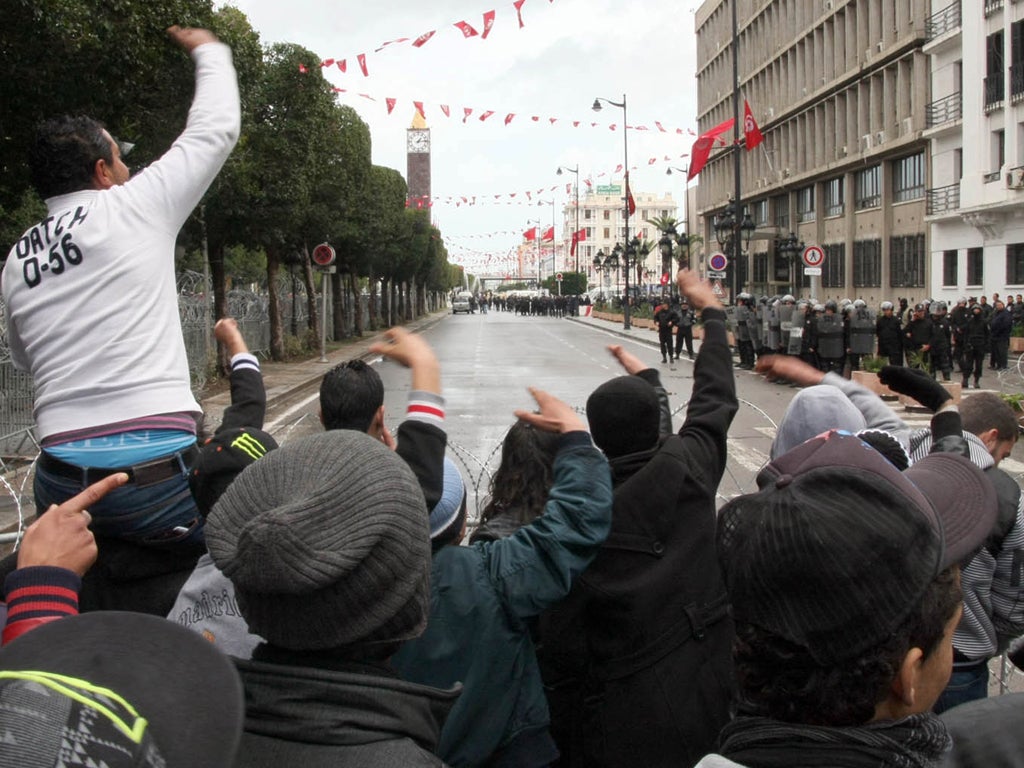 Tunisian protestors chant slogans behind barbed wire as security forces keep watch outside the Interior Ministry in Tunis, on 7 February, 2013 during a demonstration against the killing of opposition figure and human rights lawyer Chokri Belaid.