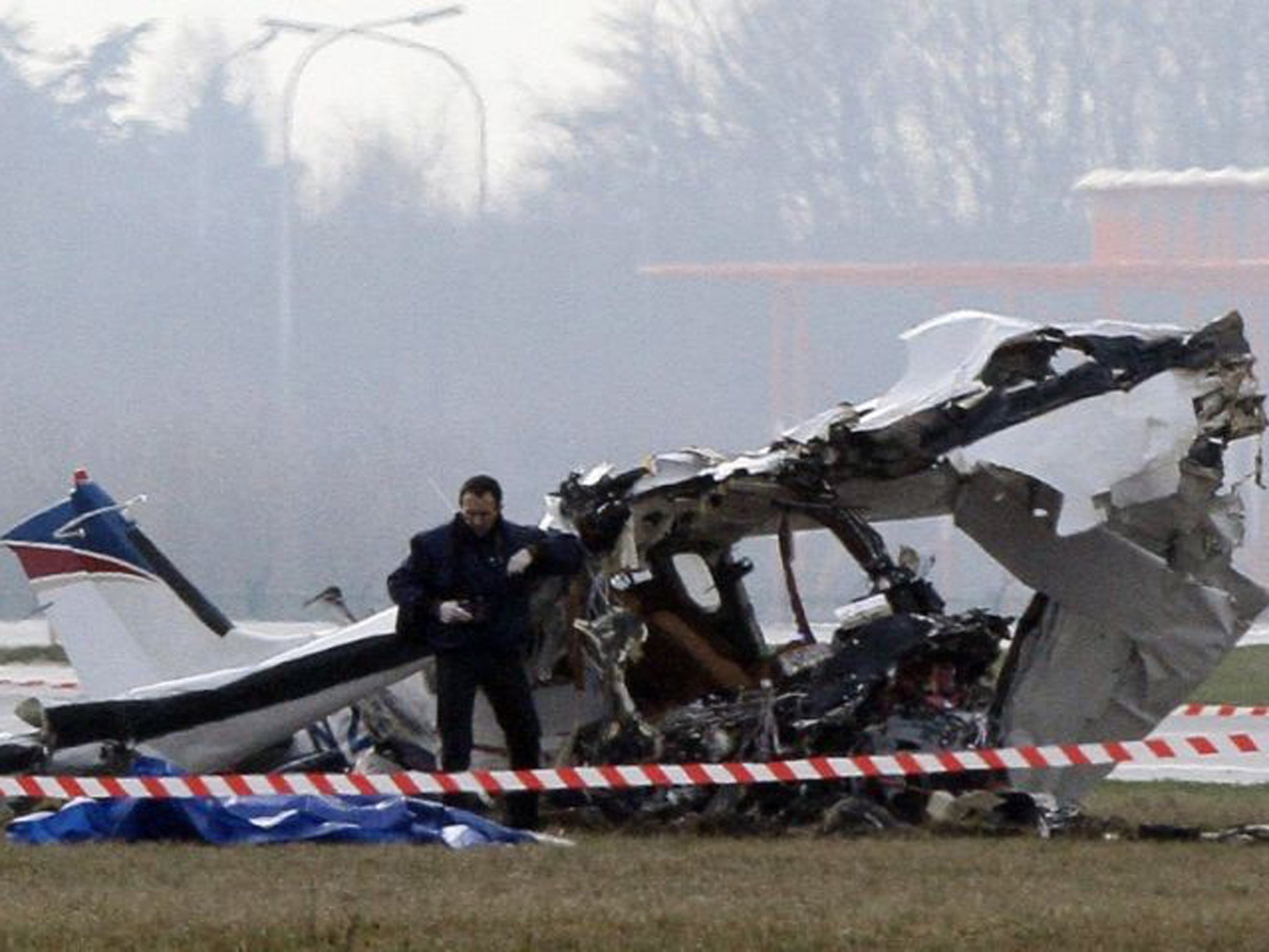 A police photographer inspects the scene of a tourist plane crash at Charleroi airport