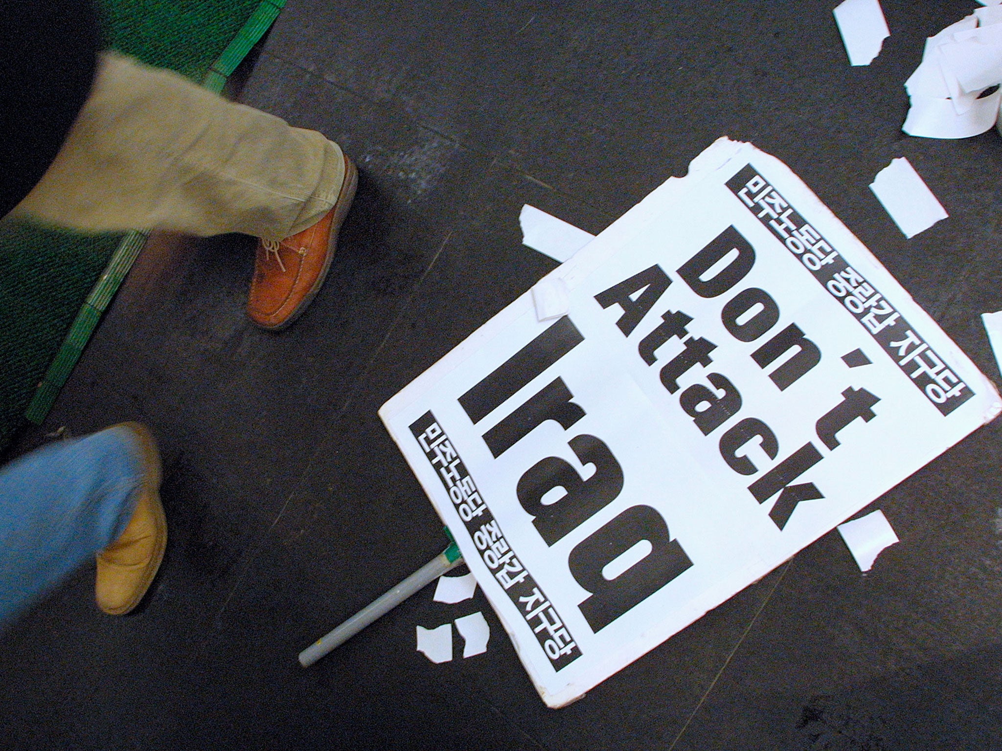 Pedestrians pass by anti-war posters during a candlelight protest against the U.S. near the U.S. embassy January 4, 2003 in Seoul, South Korea.