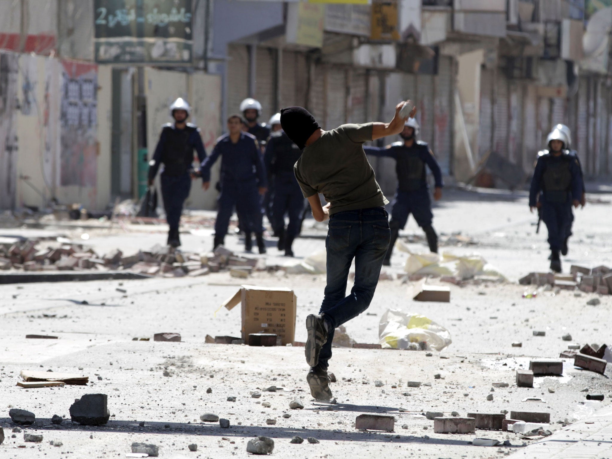 A Bahraini anti-government protester throw a stone toward riot police during clashes in Daih