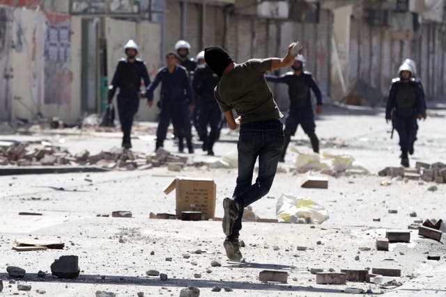 A Bahraini anti-government protester throw a stone toward riot police during clashes in Daih
