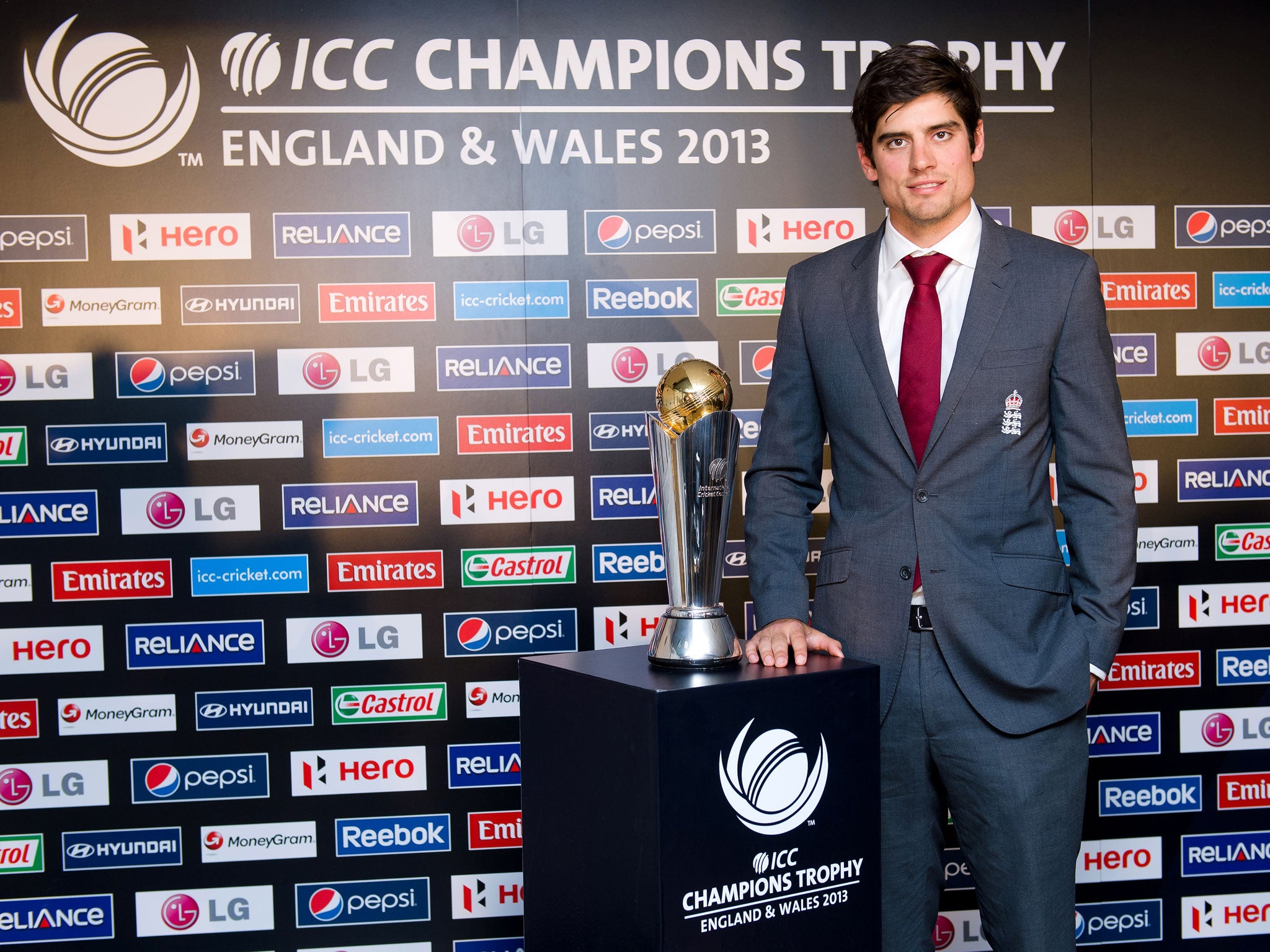 England cricket captain Alistair Cook stands next to the ICC Champions Trophy