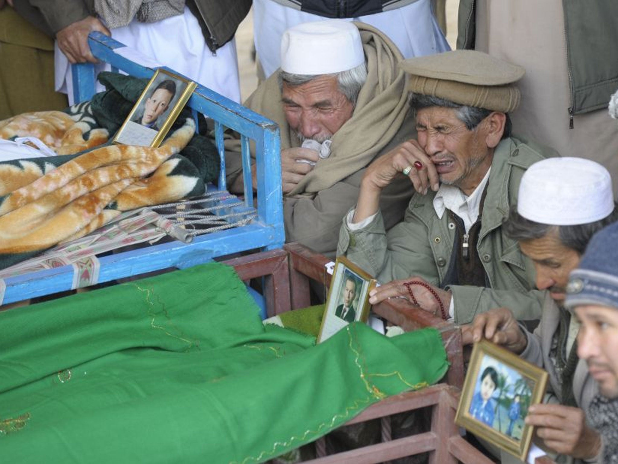Shia men weep as the bodies of adults and children killed in Saturday’s bomb attack in Quetta are prepared for burial in a mass grave yesterday, as the death toll rose to 84