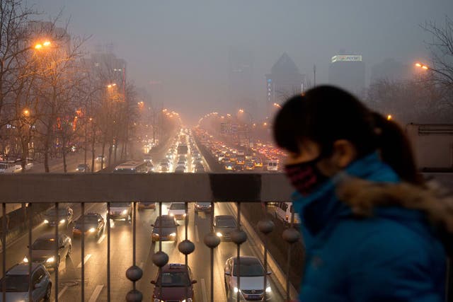 A woman wearing a mask walks over a road bridge in heavy pollution on January 28, 2013. The US embassy air quality index twitter feed recorded levels classed as 'hazardous', with a figure of 493 -- almost 20 times the World Health Organisation's safe limit.