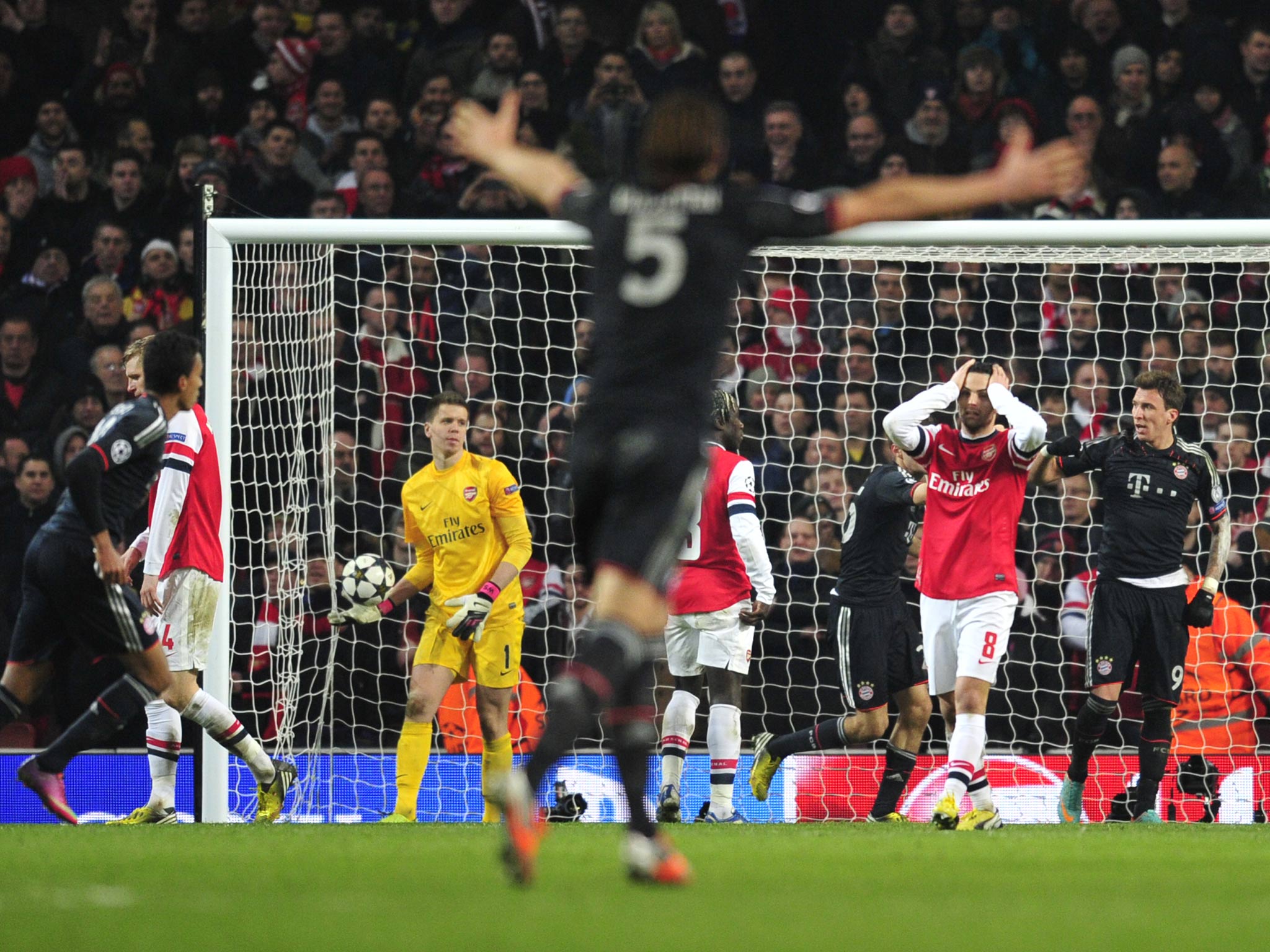 Bayern Munich players celebrate and Arsenal players react after Bayern Munich's Croatian striker Mario Mandzukic scores their third goal