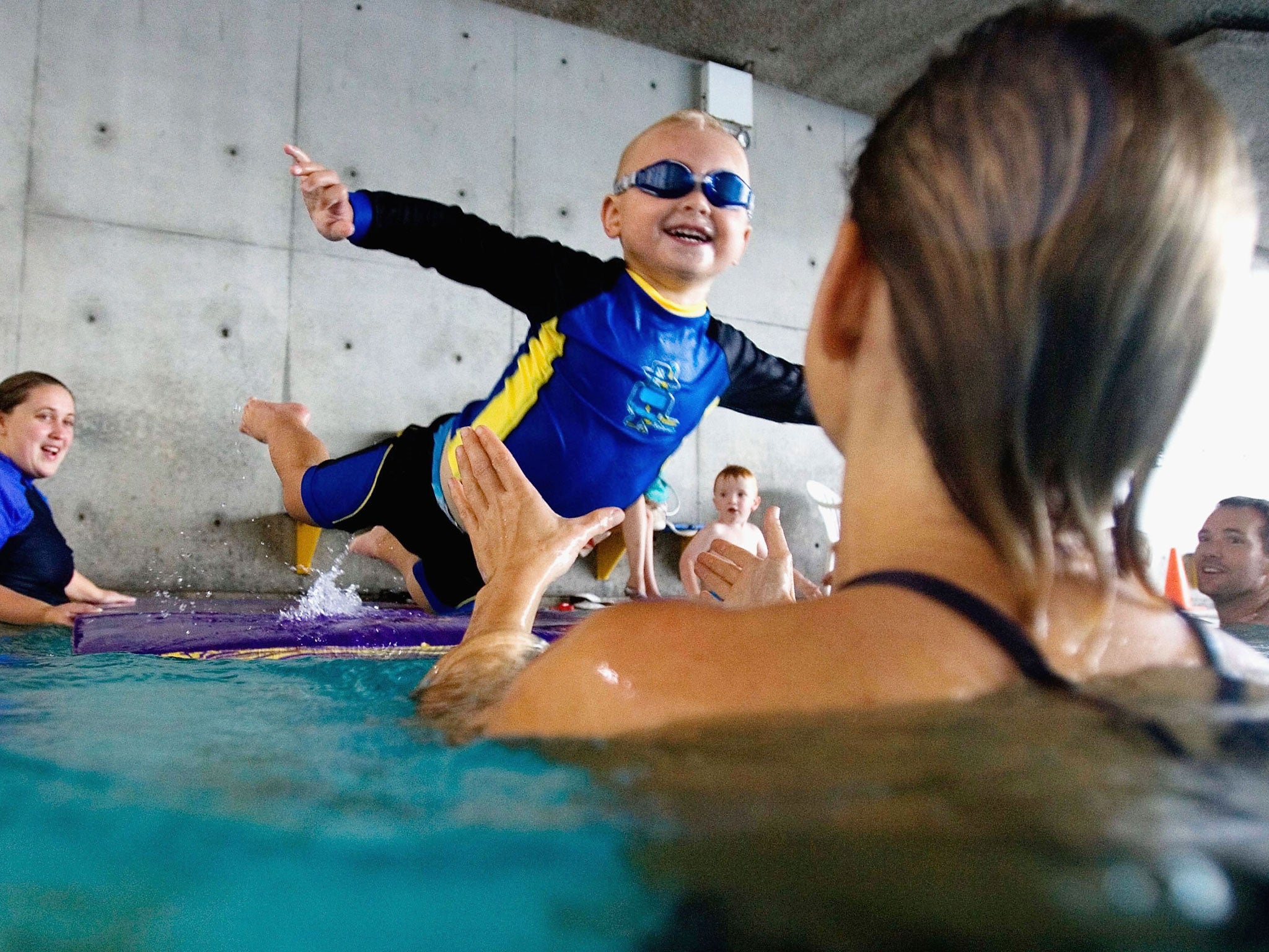A toddler jumps onto his mother during a swimming class for babies at Lane Cove pool March 16, 2007 in Sydney, Australia. According to Andy West's Non-Parent's Guide to Parenting, only lazy parents have fat children.