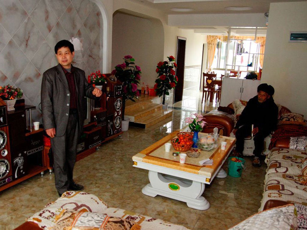 Gui Lizhong, standing in the apartment he spent four months decorating. The apartment actually belongs to Long Nengyun, who is seated