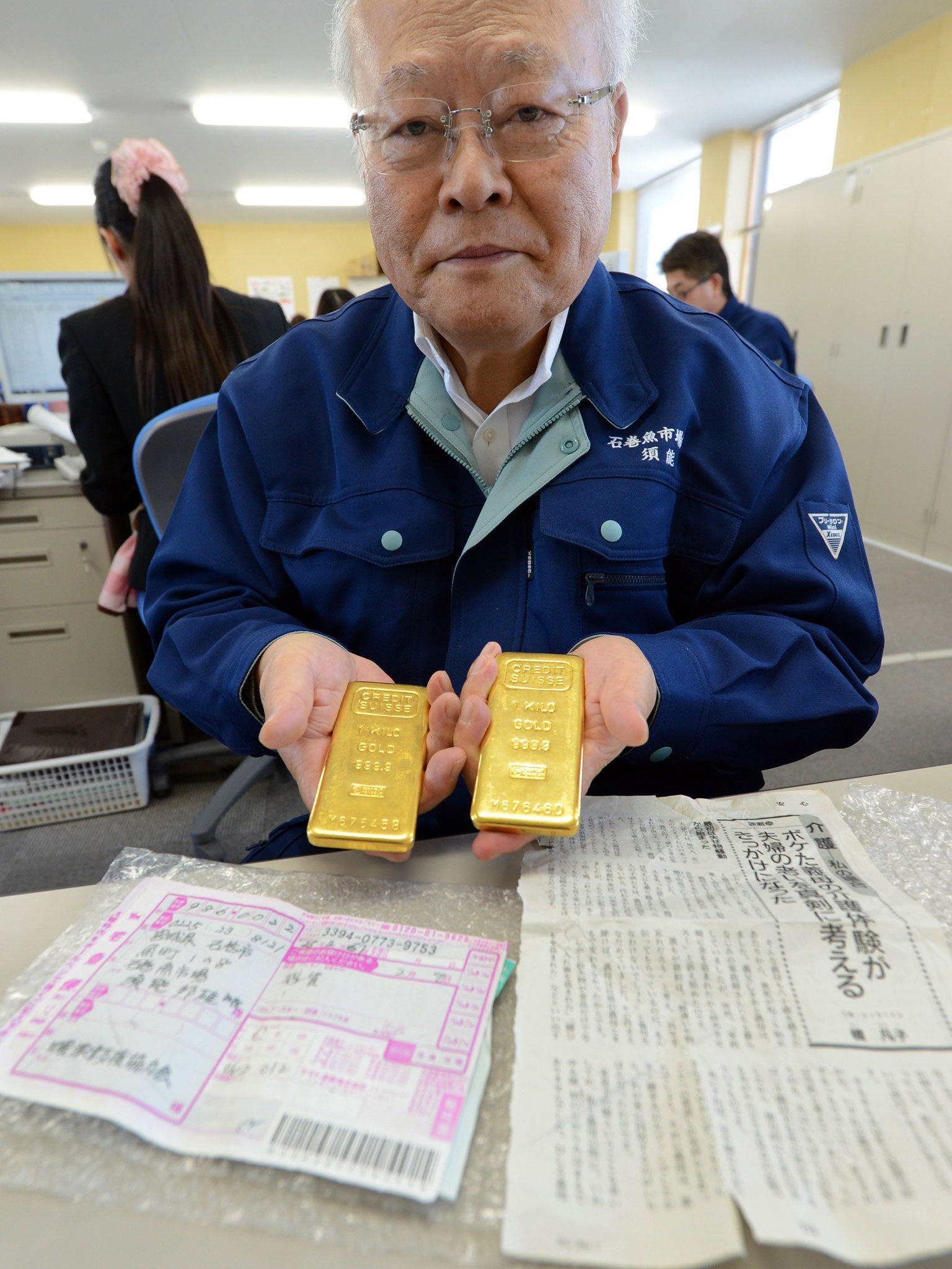 Kunio Sunow, president of the Ishinomaki Fish Market, shows off two slabs of gold each weighing one kilogram as well as the parcel's invoice and an enclosed magazine article