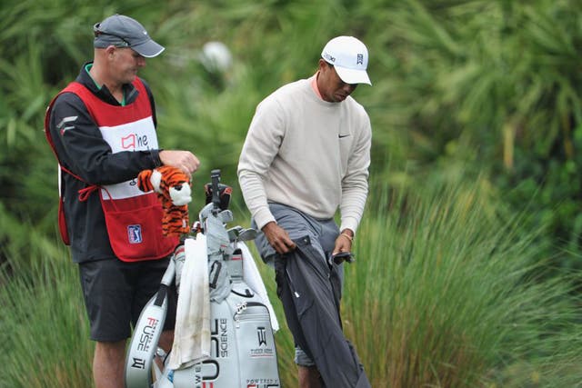 Tiger Woods pulls on his rain pants after removing his shoes at the sixth yesterday