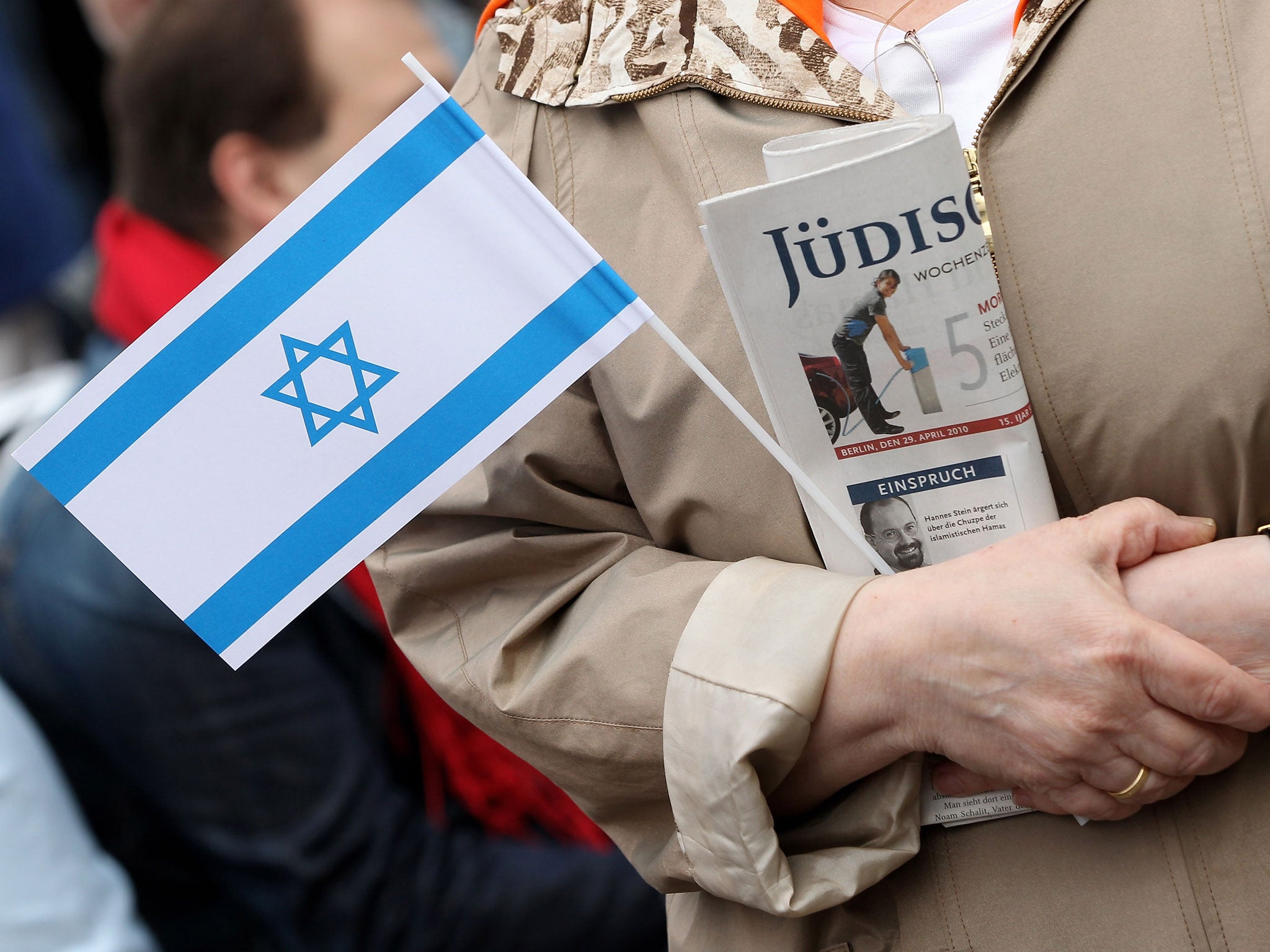 An elderly woman holds an Israeli flag and a copy of Germany's leading German-language Jewish newspaper, the 'Juedische Allgemeine,' at a street fest outside the Chabad Lubawitsch