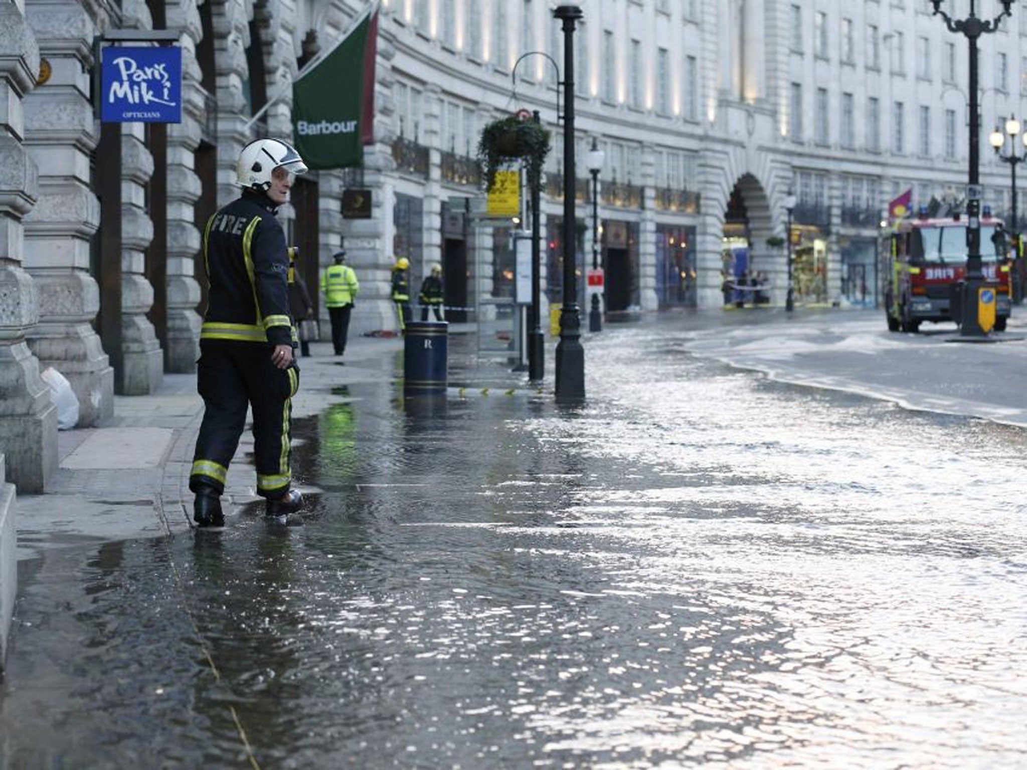 A firefighter investigates flooding caused by a burst water main on the Regent Street