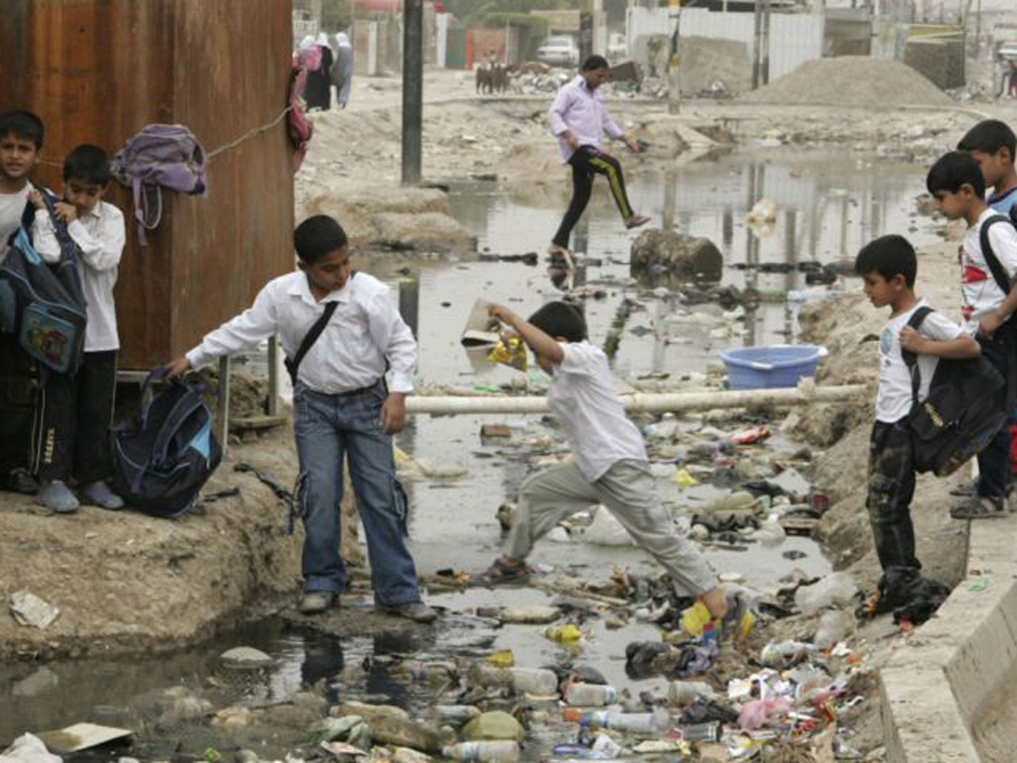 Students cross a sewage canal at Baghdad's Sadr city