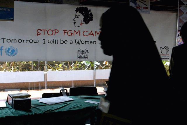A young woman walks past a campaign banner against female genital mutilation [FGM] at the venue of an International conference, 16 September 2004 in Nairobi. 
