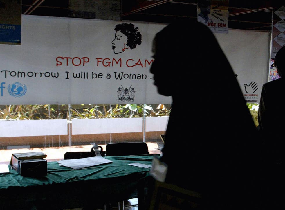 A young woman walks past a campaign banner against female genital mutilation [FGM] at the venue of an International conference, 16 September 2004 in Nairobi.