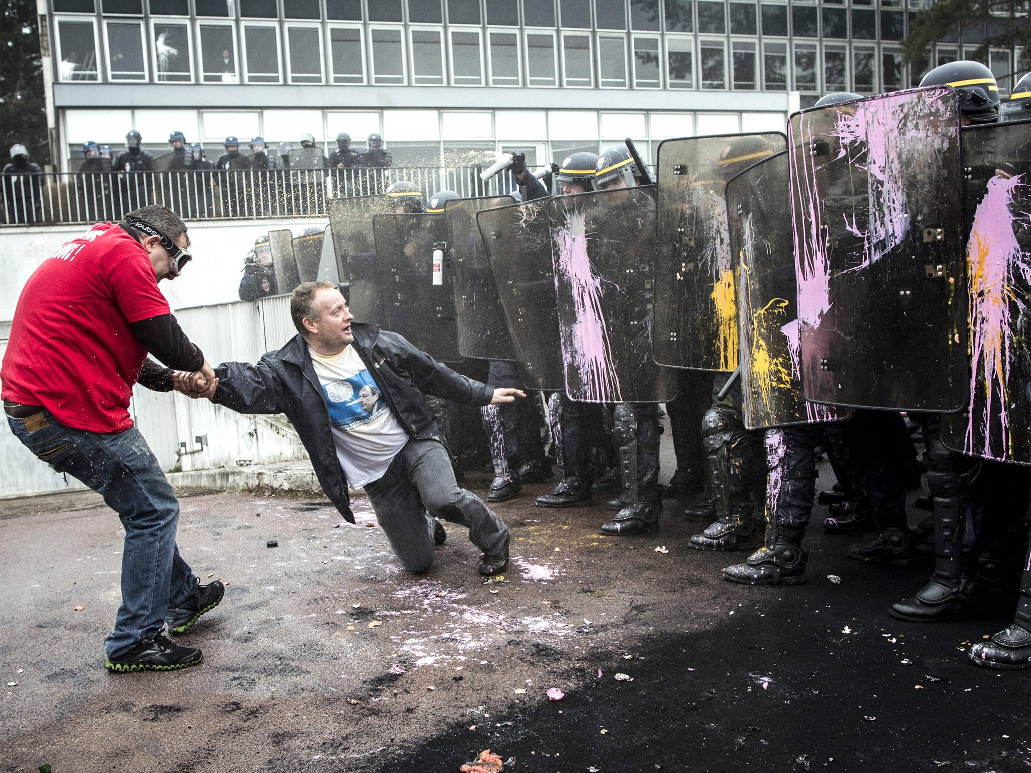 A protesting Goodyear worker pulls one of his co-workers away from riot police