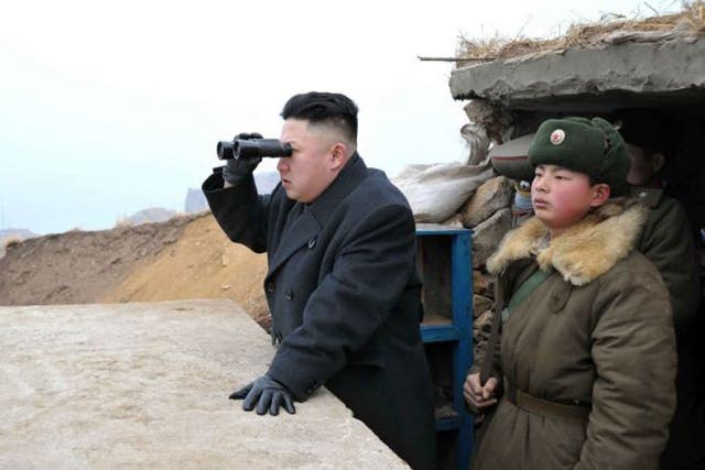 North Korean leader Kim Jong Un, center, uses binoculars to look at the South's territory from an observation post at the military unit on Jangjae islet