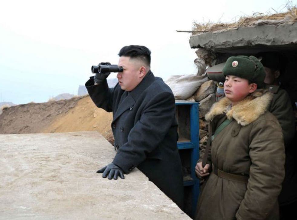 North Korean leader Kim Jong Un, center, uses binoculars to look at the South's territory from an observation post at the military unit on Jangjae islet