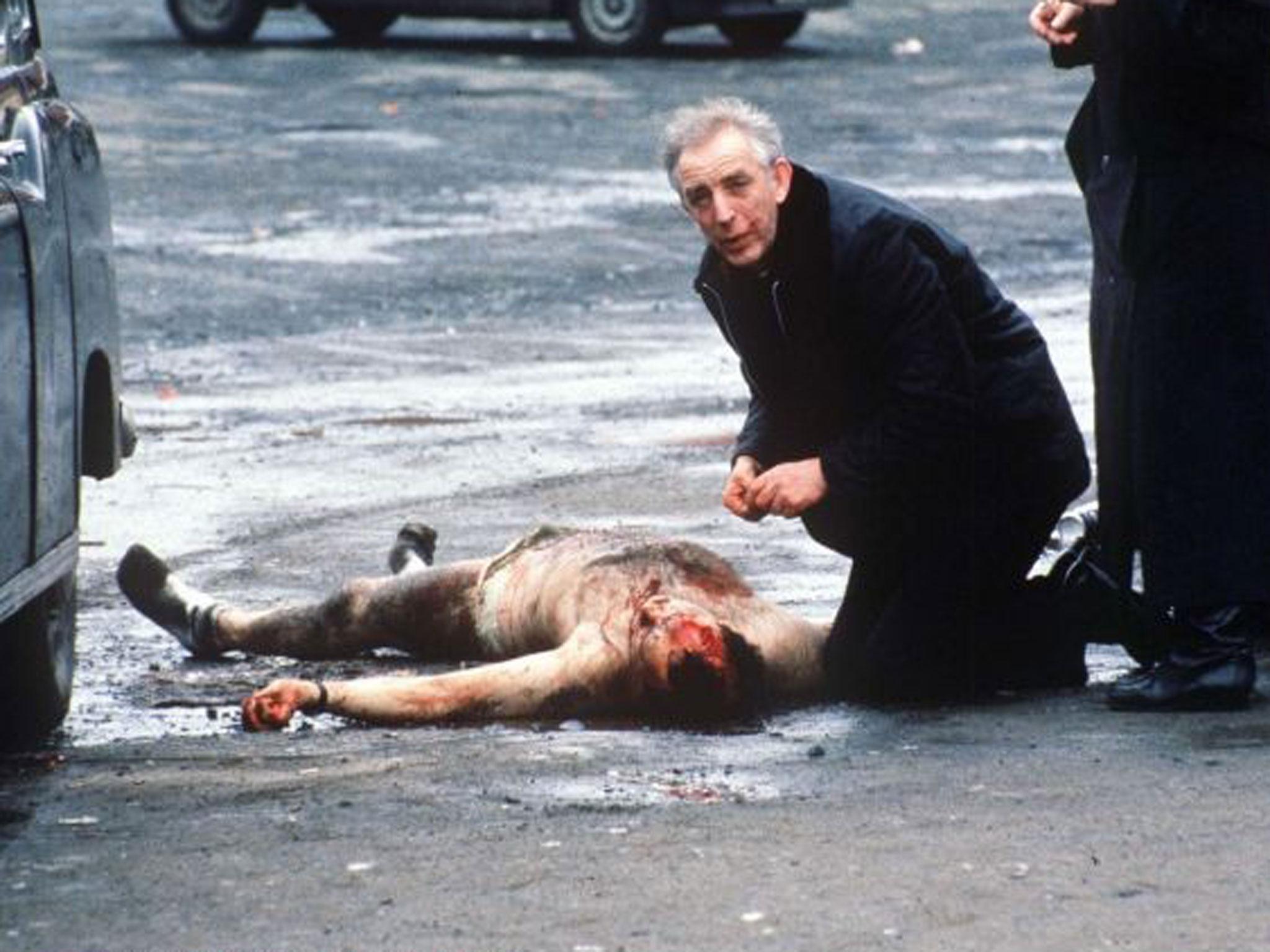 Father Alec Reid giving last rites to one of the two soldiers killed by a mob at the funeral of an IRA member shot by loyalist gunman Michael Stone (Rex)