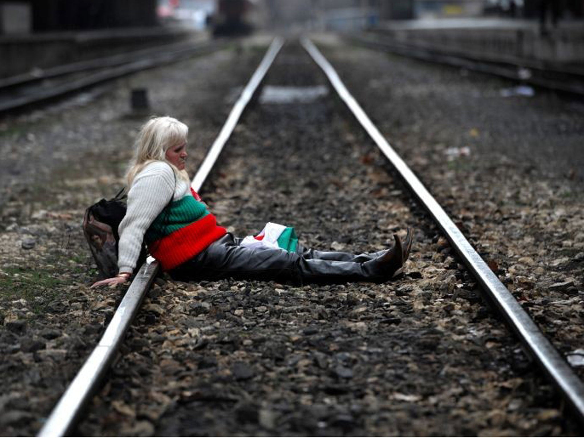 A protester sits on the tracks during a blockade of the railway next to Sofia Central railway station as part of anti-monopoly protest
