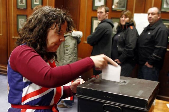 Falkland Islander Joan Turner, wearing a dress with the Union Jack colours, casts her vote at the Town Hall polling station in Stanley