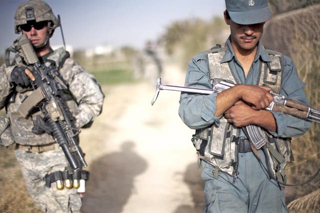 An Afghan policeman attached with US soldiers holds his machine gun during a patrol along the outskirts of Kandahar City
