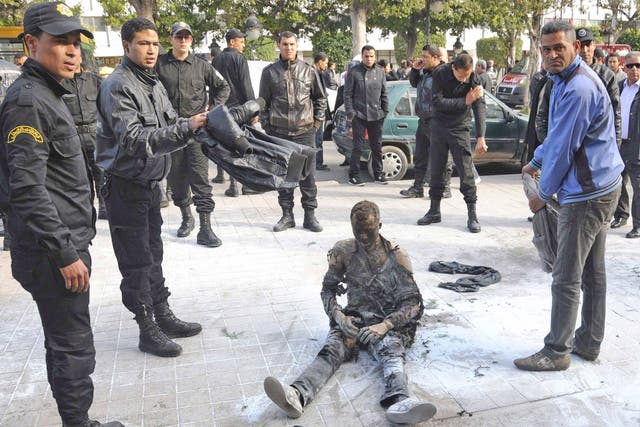 A young Tunisian man who set himself on fire is surrounded by security forces in Tunis