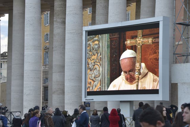 Faithful stand on St Peter's square to watch the first mass by Pope Francis on a giant screen on March 14, 2013 at the Vatican.