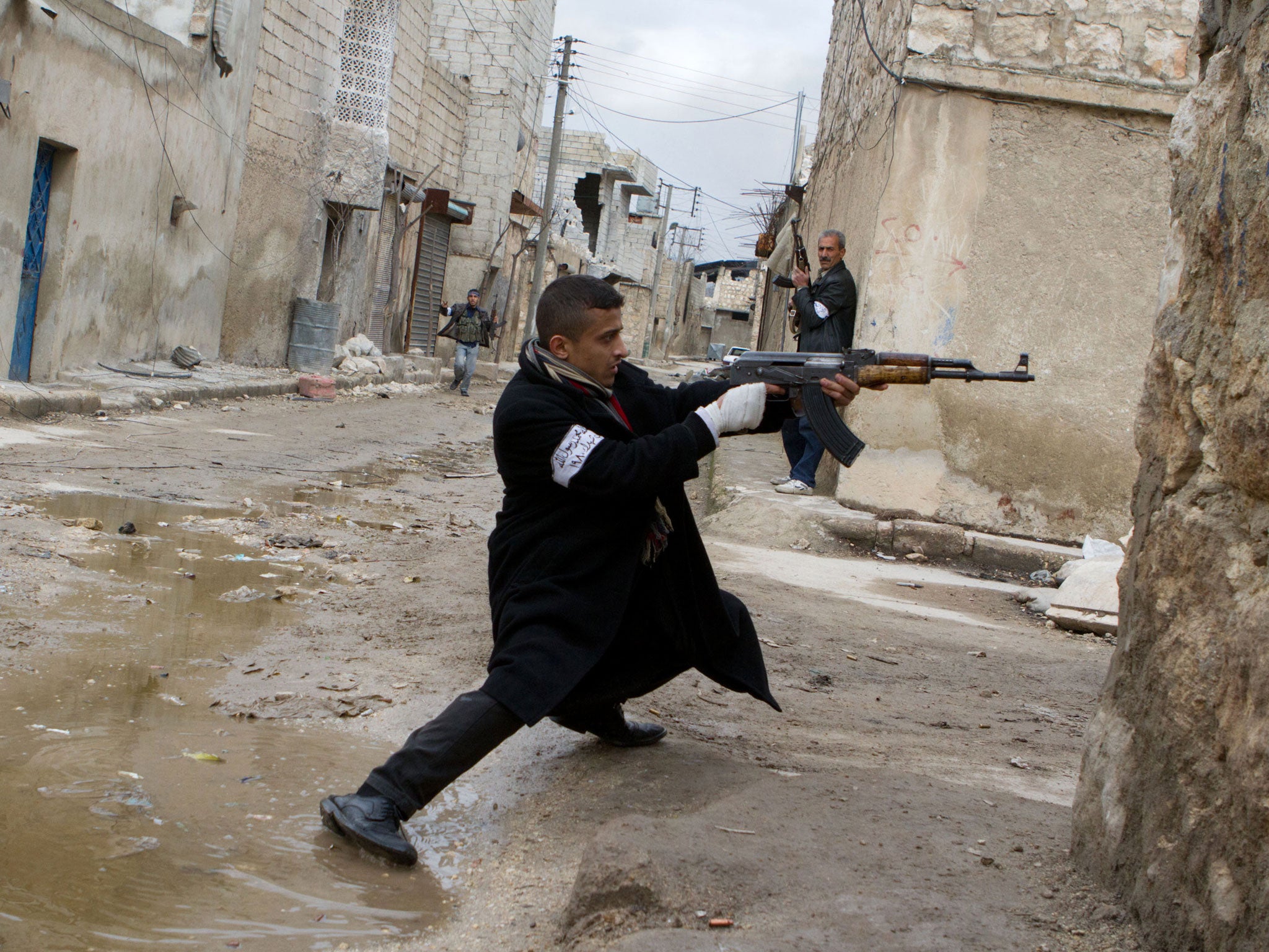 A Syrian rebel aims his weapon during clashes with government forces in the streets near Aleppo international airport in northern Syria on March 4, 2013.