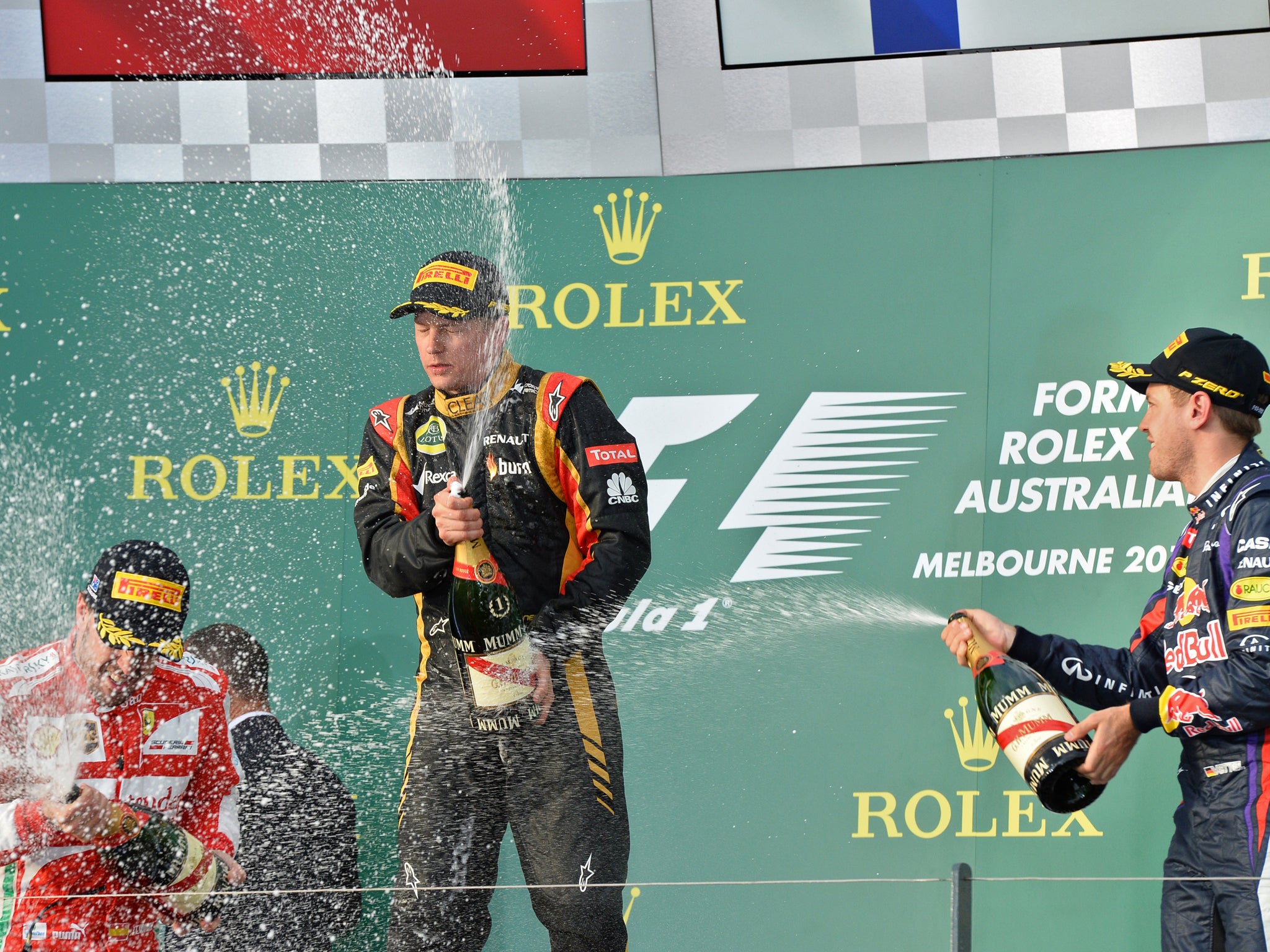 Lotus driver Kimi Raikkonen after his victory, next to second placed Ferrari driver Fernando Alonso (L) and third placed Red Bull driver Sebastian Vettel