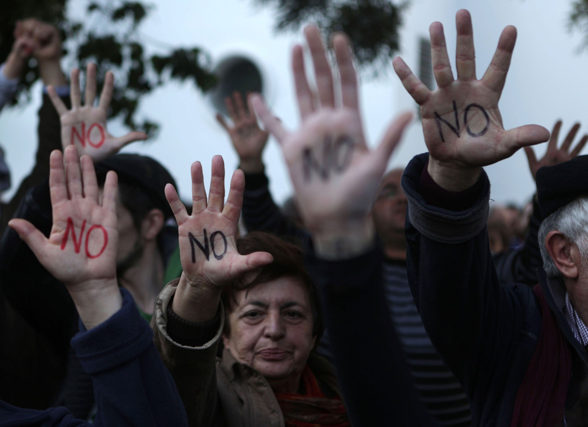 Cypriots show their palms reading 'No' during a protest against an EU bailout deal outside the parliament in Nicosia on March 18, 2013.