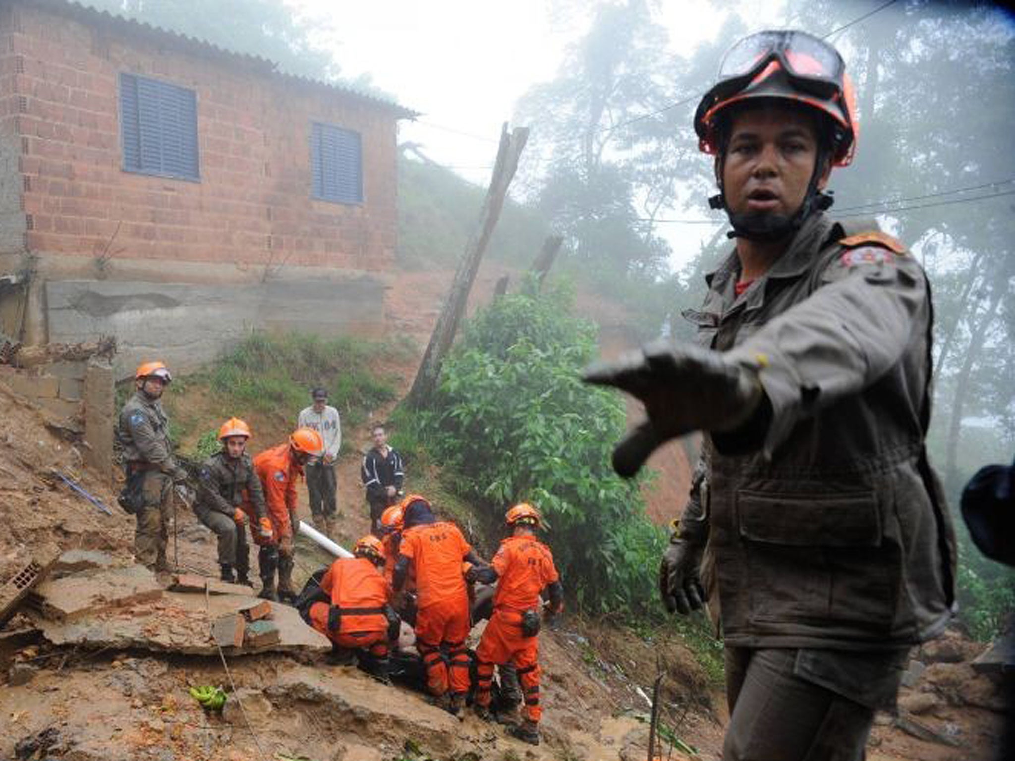 A rescue worker gestures as his colleagues carry the body of a victim of a mudslide in Petropolis, near Rio de Janeiro