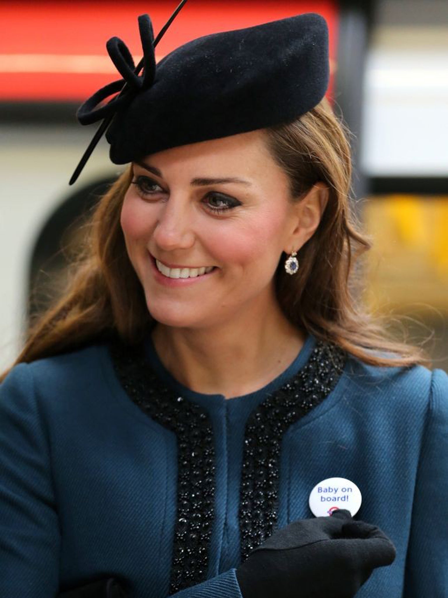 Kate, Duchess of Cambridge, holds a badge that reads "Baby on Board"
