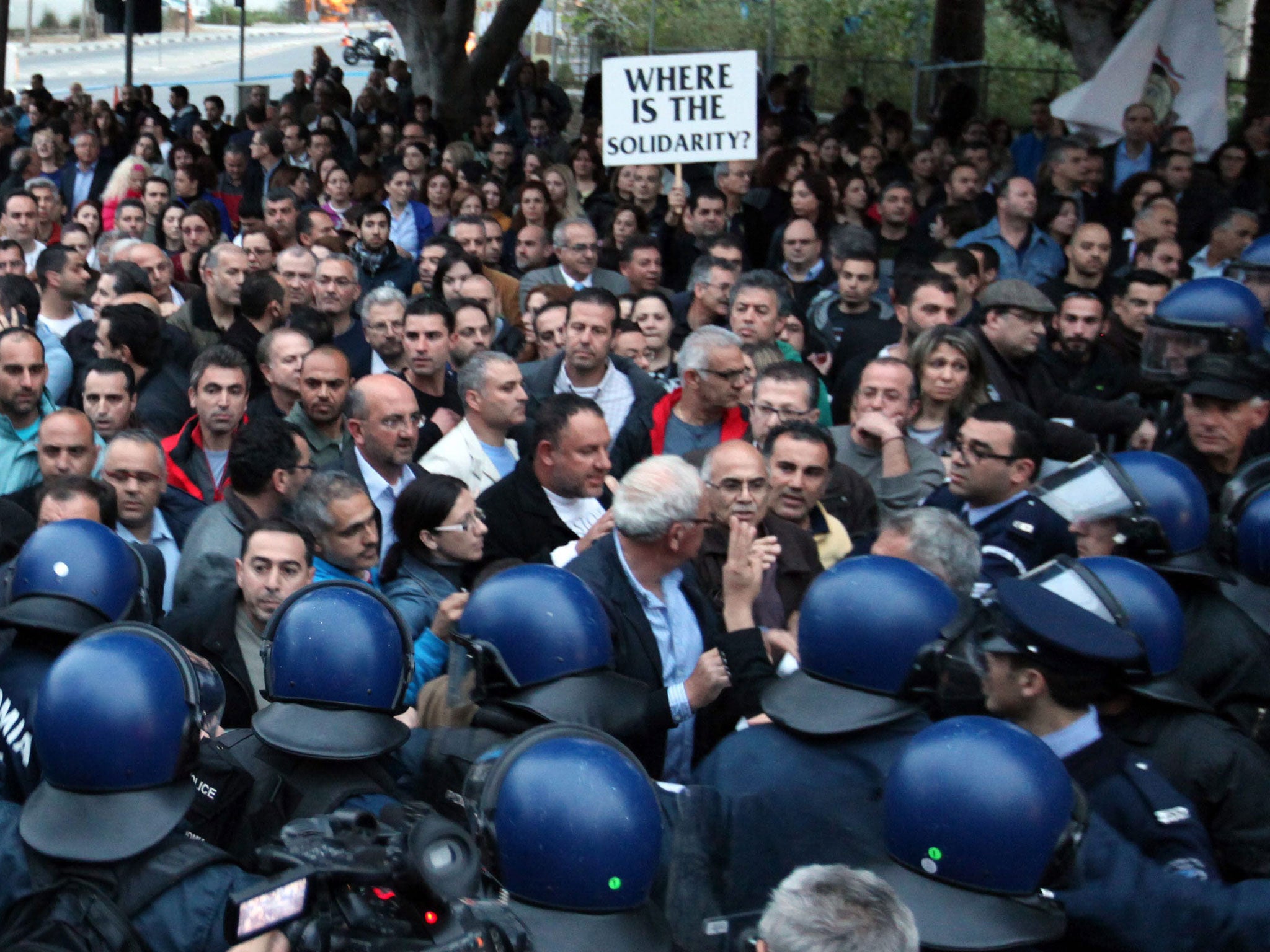 Employees of  Laiki Bank, the second largest on Cyprus, face a heavy line of riot police as they demonstrate outside the House of Representatives in Nicosia