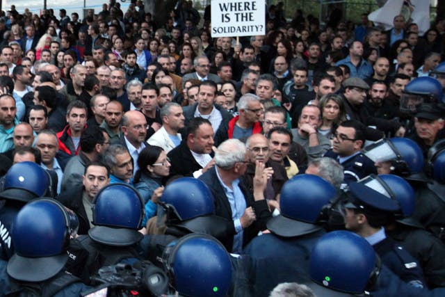 Employees of  Laiki Bank, the second largest on Cyprus, face a heavy line of riot police as they demonstrate outside the House of Representatives in Nicosia