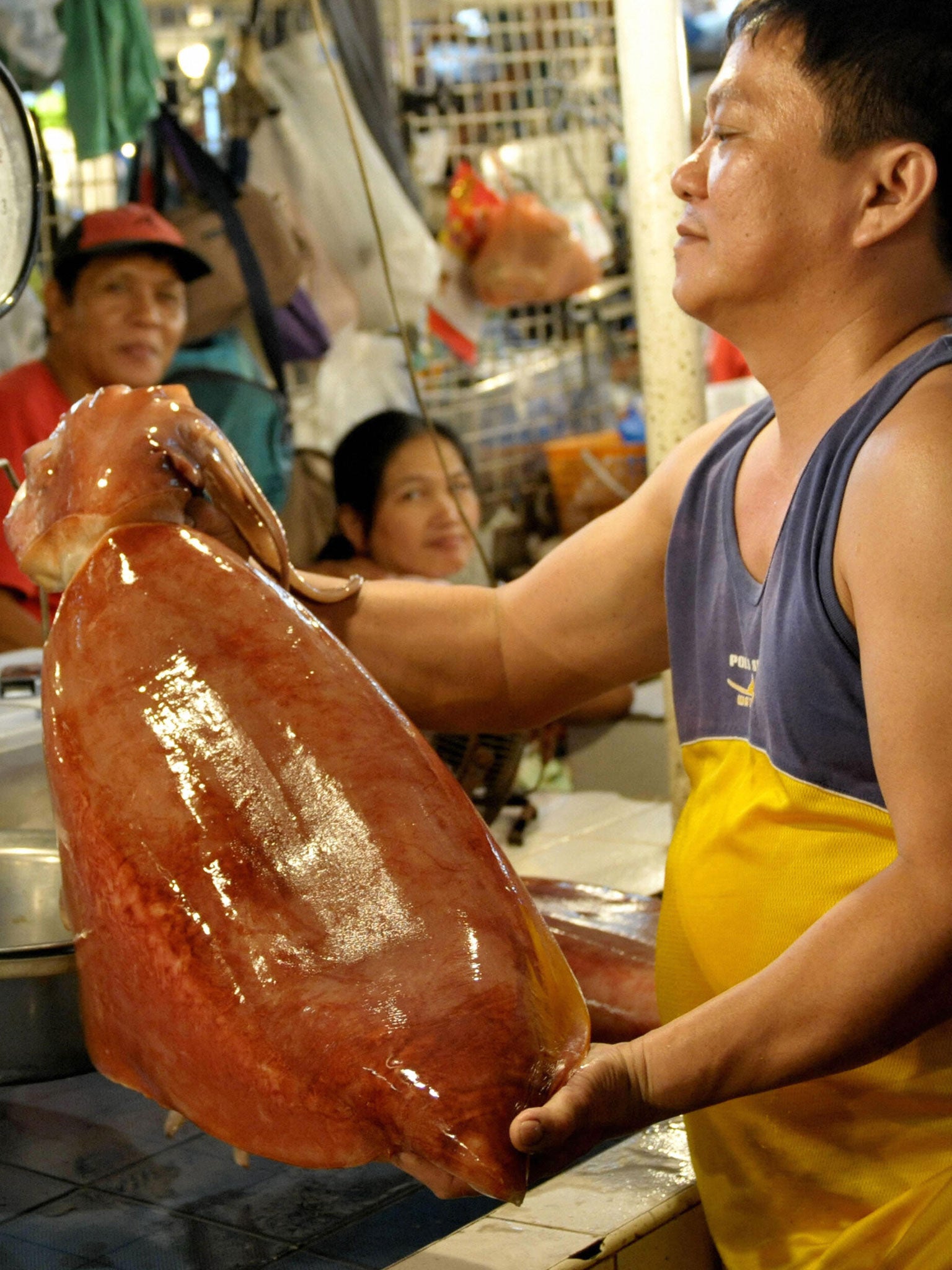A fishmonger weighs a squid at the farmers market in Quezon City, in the Philippines